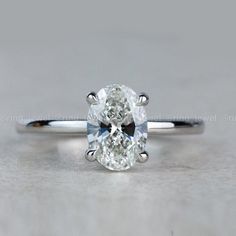 an oval cut diamond ring on top of a white surface with the center stone in the middle