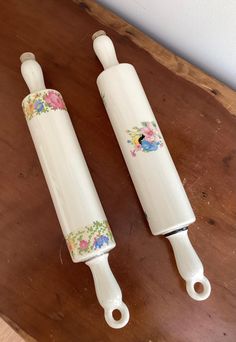 two ceramic toothbrush holders sitting on top of a wooden table