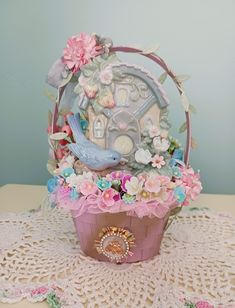 there is a basket with flowers and a bird in it sitting on the doily