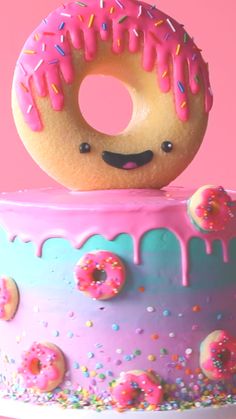 a donut sitting on top of a cake with pink frosting and sprinkles