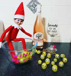 an elf is sitting in a bowl next to some grapes