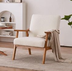 a white chair sitting on top of a wooden floor next to a potted plant