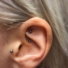 a woman's ear with three piercings on it