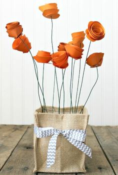 some orange flowers are in a burlock vase on a wooden table with a bow