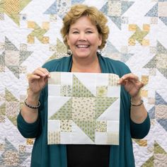 a woman holding up a piece of quilt