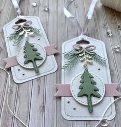 two tags with christmas trees on them and ribbons hanging from the top, along with twine string