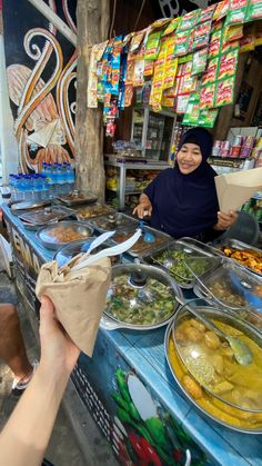 a woman standing in front of a table filled with food next to a man holding a paper bag