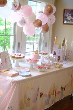 a table topped with lots of pink and gold balloons