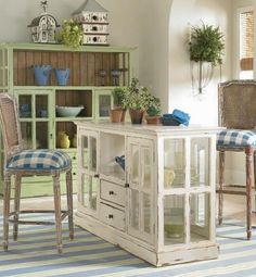 an old windowed cabinet in the middle of a room with chairs and stools