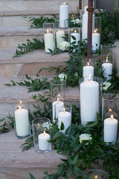 candles are lined up on the steps with greenery