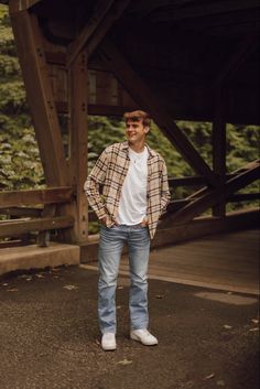 a young man standing in front of a wooden structure with his hands on his hips