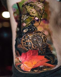 a woman's leg with an intricate tattoo design on it and autumn leaves in the background