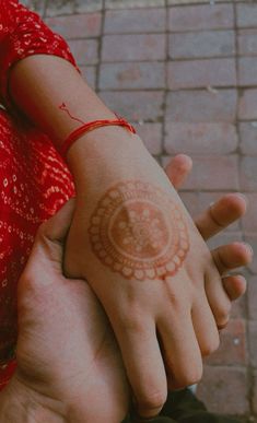 two people holding each other's hands with henna tattoos on their arms and wrist