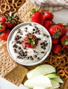 a white plate topped with crackers, strawberries and chocolate chips next to pretzels