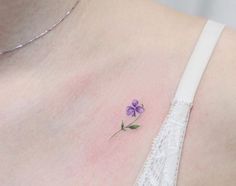 a small purple flower on the back of a woman's shoulder