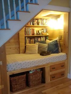 a book shelf under the stairs is filled with books