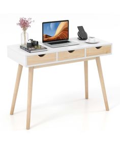 a laptop computer sitting on top of a white desk next to a vase with flowers