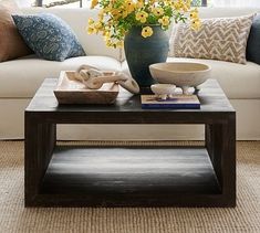 a living room with a couch, coffee table and flowers in a vase on top