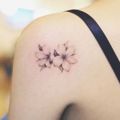 a close up of a woman's back shoulder with flowers on the left side