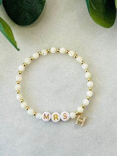 This bride bracelet with dainty initial-to-be and is a sweet and fun personalized gift for the future bride. Perfect gift for bride at bachelorette party or bridal shower. Beaded with genuine mother of pearl and 18k gold filled beads that are tarnish resistant and made to last opposed to the more commonly seen gold plated. Other coordinating pieces in shop. Beaded on high quality stretch cord and secured..     3mm 18k gold filled beads   4mm mother of pearl beads   7mm gold filled initial with c Personalized Bracelets For Bridesmaid Gift On Valentine's Day, White Hypoallergenic Dainty Name Bracelet, Dainty White Bracelets For Bridesmaid Gift, White Dainty Beaded Bracelets For Bridesmaid Gift, Dainty White Beaded Bracelets For Bridesmaids, Dainty Hypoallergenic Charm Bracelet For Weddings, Personalized Charm Bracelet For Bridesmaids, Personalized Charm Bracelet For Bridesmaid Gift On Mother's Day, Dainty Adjustable Name Bracelet For Bridesmaid Gift