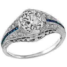 This magnificent platinum engagement ring is centered with a sparkling old mine cushion cut diamond that weighs 1.28ct. and is graded I color with SI1 clarity. The center stone is accentuated by sapphire and diamond accents. The ring is currently size 5 1/4, and can be resized. Inventory #E91637NPSS Cushion Cut Sapphire Ring, Diamond Sapphire Engagement Ring, Antique Engagement Rings Vintage, Platinum Diamond Engagement Rings, Unusual Jewelry, Sapphire Engagement Ring, Platinum Engagement Rings, Deco Engagement Ring, Cushion Cut Diamonds