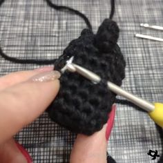 someone is crocheting the end of a piece of black yarn with two knitting needles