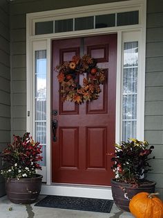 the front door is decorated for fall with pumpkins and other plants on the doorstep