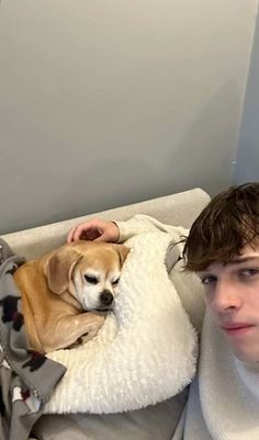 a young man laying in bed with his dog