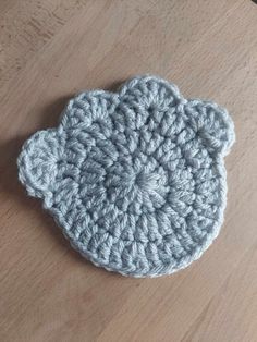 a crocheted dishcloth sits on a wooden surface, ready to be used as a coaster