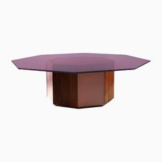 an oval shaped table with a purple glass top and wooden base, against a white background