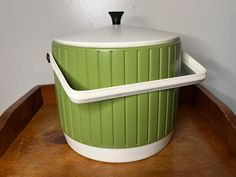 a green and white container sitting on top of a wooden table next to a wall