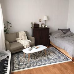 a living room with a couch, coffee table and piano in front of the bed