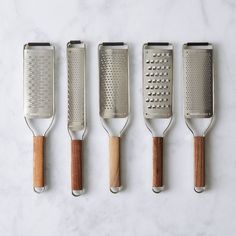 four kitchen utensils lined up next to each other on a marble counter top