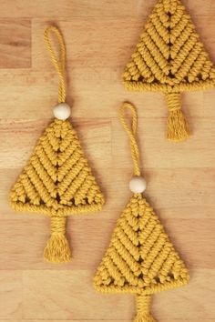 three small crocheted ornaments on a wooden surface, one is yellow and the other is white