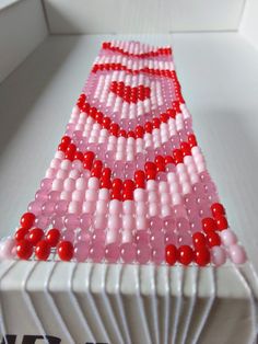 a pink and red beaded object sitting on top of a white table next to a window