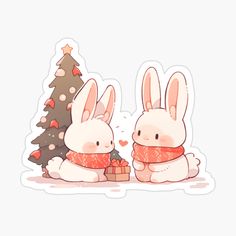 two rabbits sitting next to each other near a christmas tree