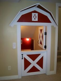 a red and white barn shaped shelf with lights on it's sides in a room