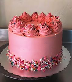 a pink frosted cake with sprinkles on top