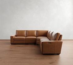 a brown leather couch sitting on top of a wooden floor next to a white wall