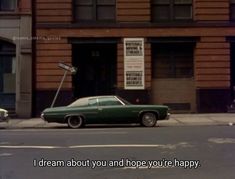 a green car parked on the side of a street next to a tall brown building