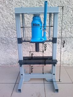 a blue water pump sitting on top of a white stand next to a wall with measurements