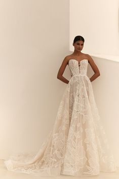 a woman in a wedding dress standing against a wall