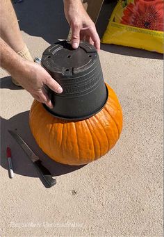 a person is placing an item on top of a pumpkin