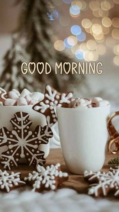 two cups filled with hot chocolate next to cookies and snowflakes on a table