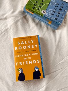 two books sitting on top of a bed next to each other in front of a white sheet