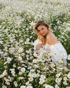 a woman is sitting in a field of daisies