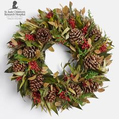 a wreath with pine cones, berries and evergreen leaves is displayed against a white background