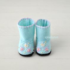 a pair of blue baby boots with flowers on the inside and bottom, sitting on a white surface