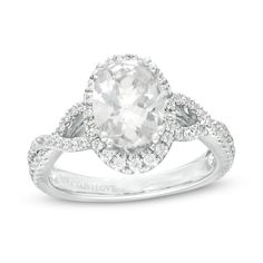 From the Vera Wang Love Collection, this diamond engagement ring is an elegant display of your affection. Fashioned in 14K white gold, this splendid look features a 2 ct. certified oval-shaped diamond boasting a color rank of I and clarity of Si2. A halo of diamonds highlights the center stone in shimmer while the twist ribbons of the split shank sparkle with diamonds. Along the gallery, a pair of princess-cut bright blue sapphires - the signature of the collection and a symbol of faithfulness a Vera Wang Engagement Rings, Twist Engagement Ring, 2nd Wedding, Twisted Ribbons, Wedding Rings Princess Cut, Engagement Rings Twisted, Diamond Frame, Peoples Jewellers, Wedding Dreams