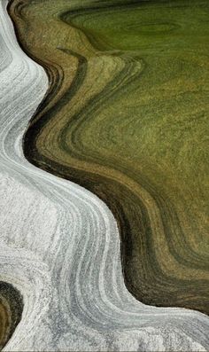 an aerial view of green and brown grass with white swirls in the foreground